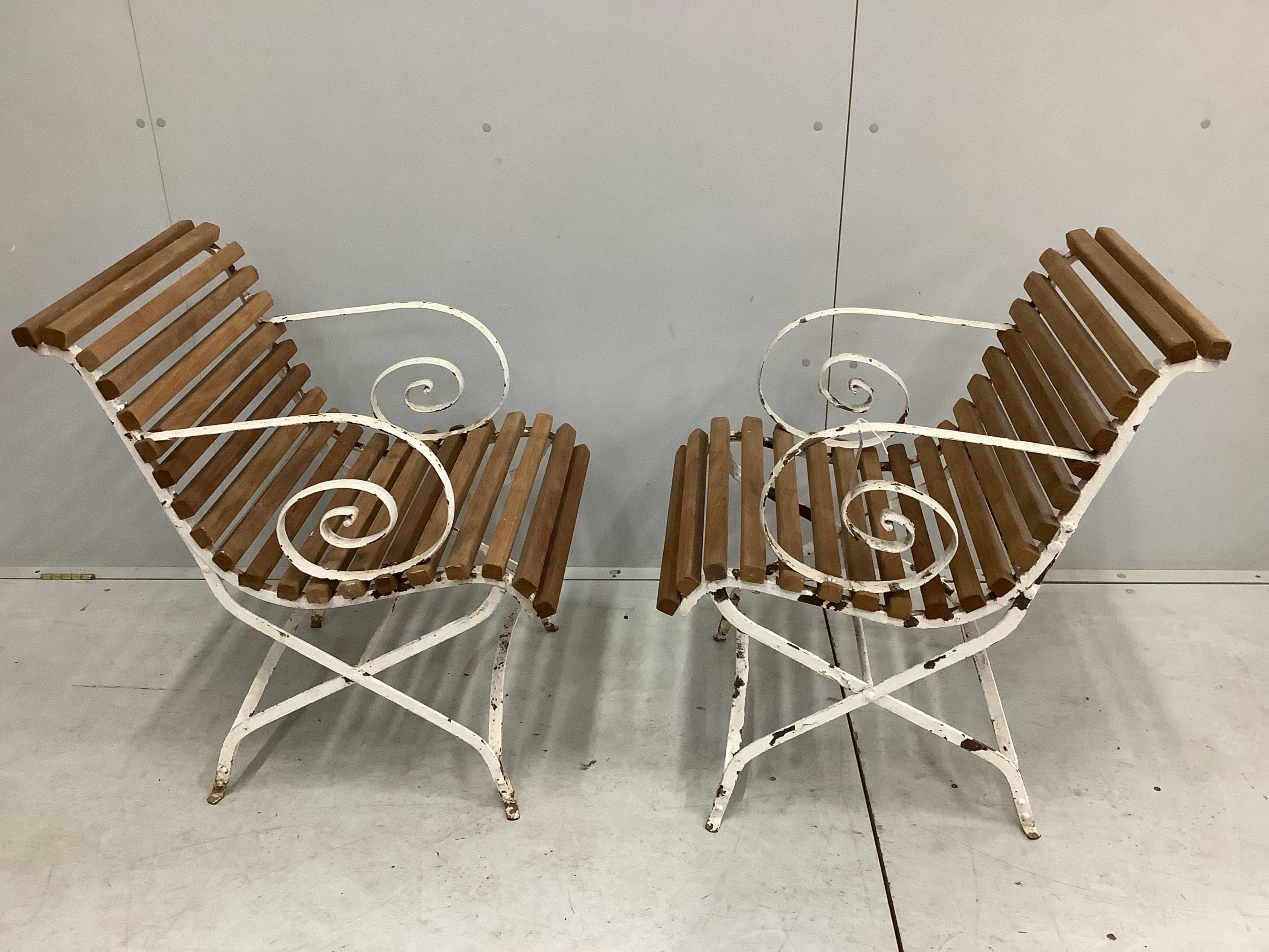 A pair of white painted wrought iron teak slatted garden elbow chairs, width 49cm, height 80cm. Condition - some paint loss, otherwise fair